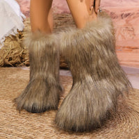 Furry boots worn by a person on a textured surface with a blurred background