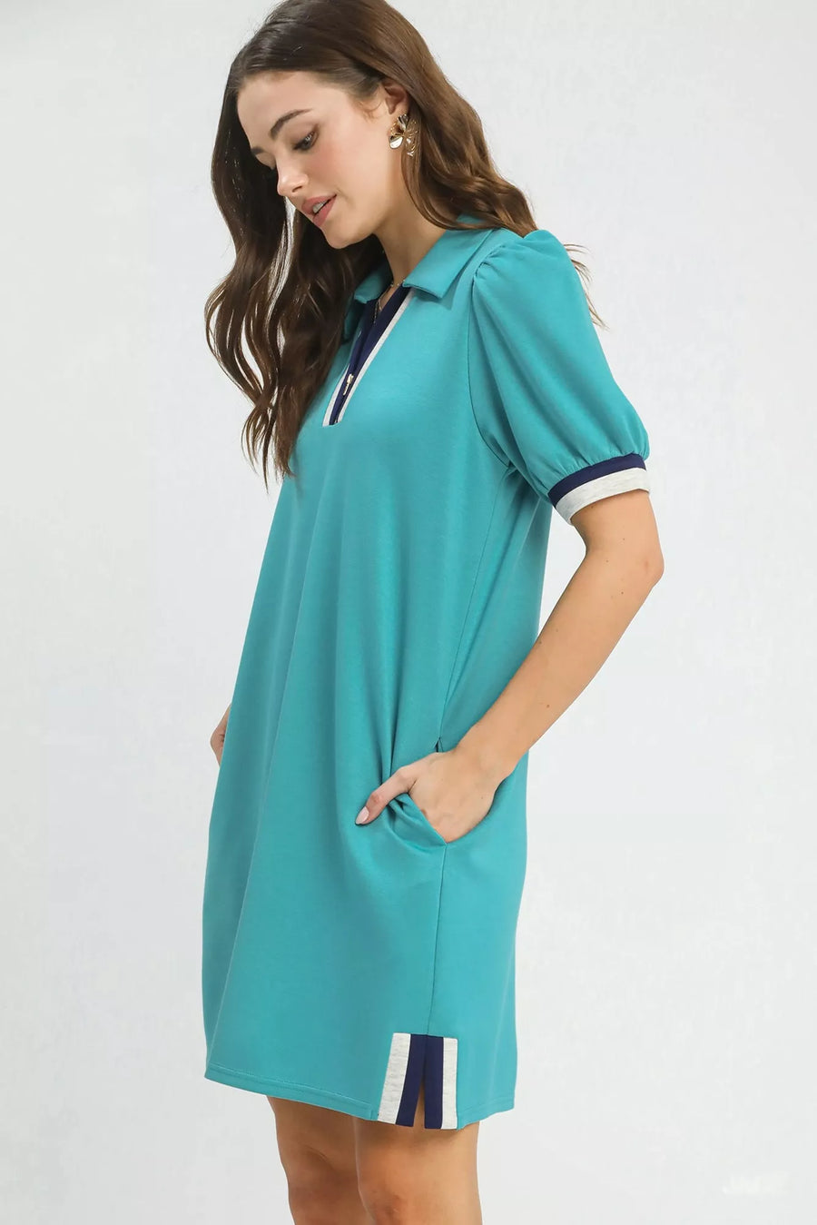 Woman wearing a teal dress with white accents on a white background