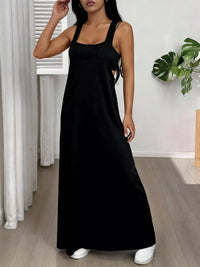 Woman wearing a black dress in a room with white curtains and a plant.