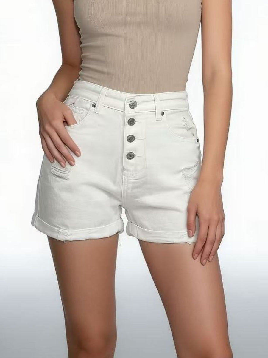 White denim shorts with button details worn by a person on a plain background