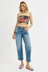 Woman wearing a floral bandeau top and blue jeans on a white background