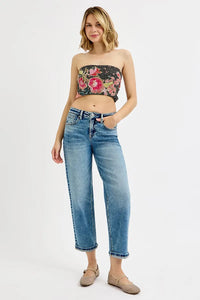Woman wearing a floral bandeau top and blue jeans on a white background