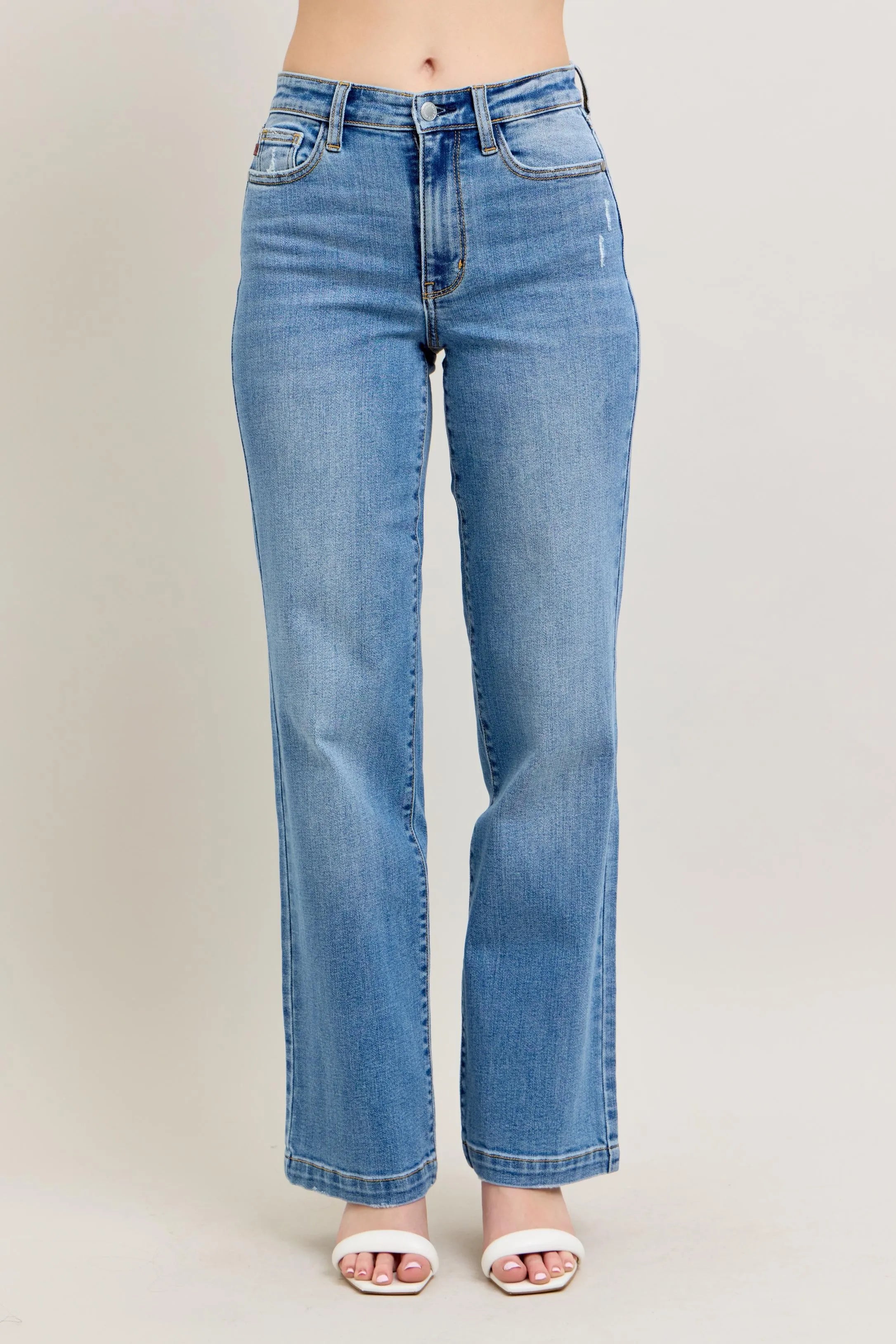 Blue jeans worn by a person on a plain background