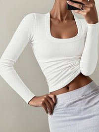 White long-sleeve crop top worn by a person on a plain background