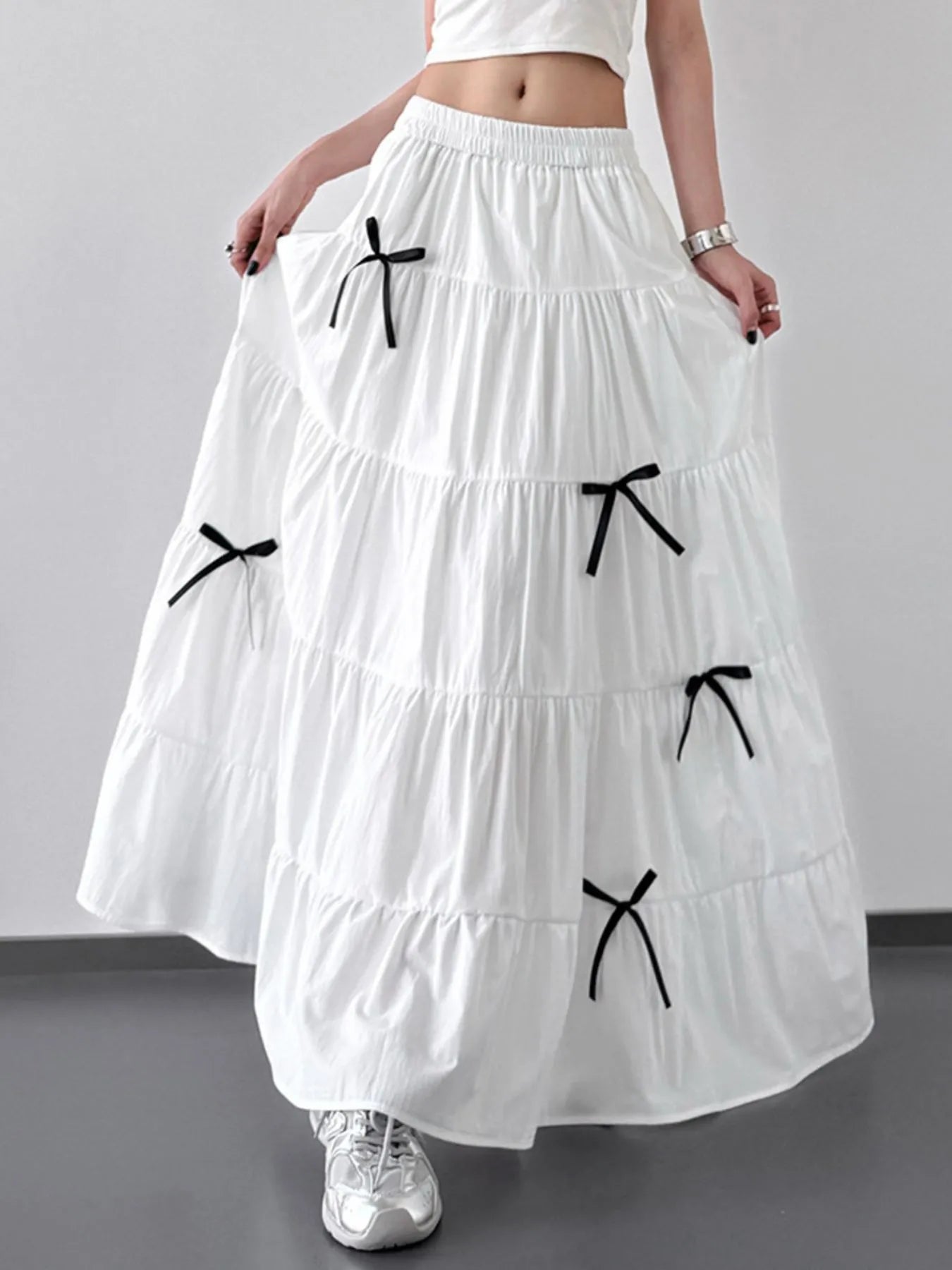 White tiered skirt with black bows worn by a person on a plain background