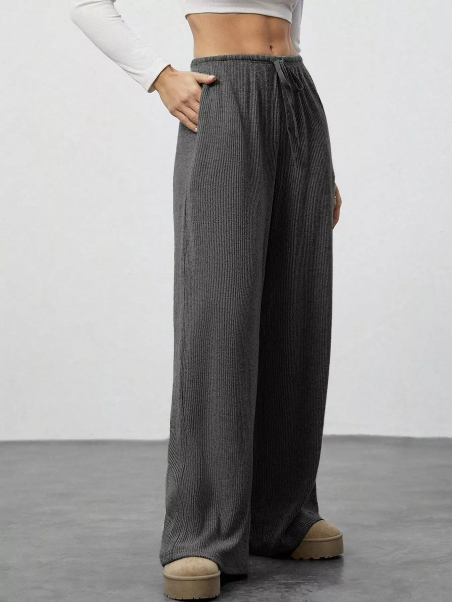 Person wearing gray wide-leg pants on a plain background