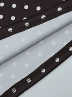 Close-up of black polka dot trim on light gray fabric background