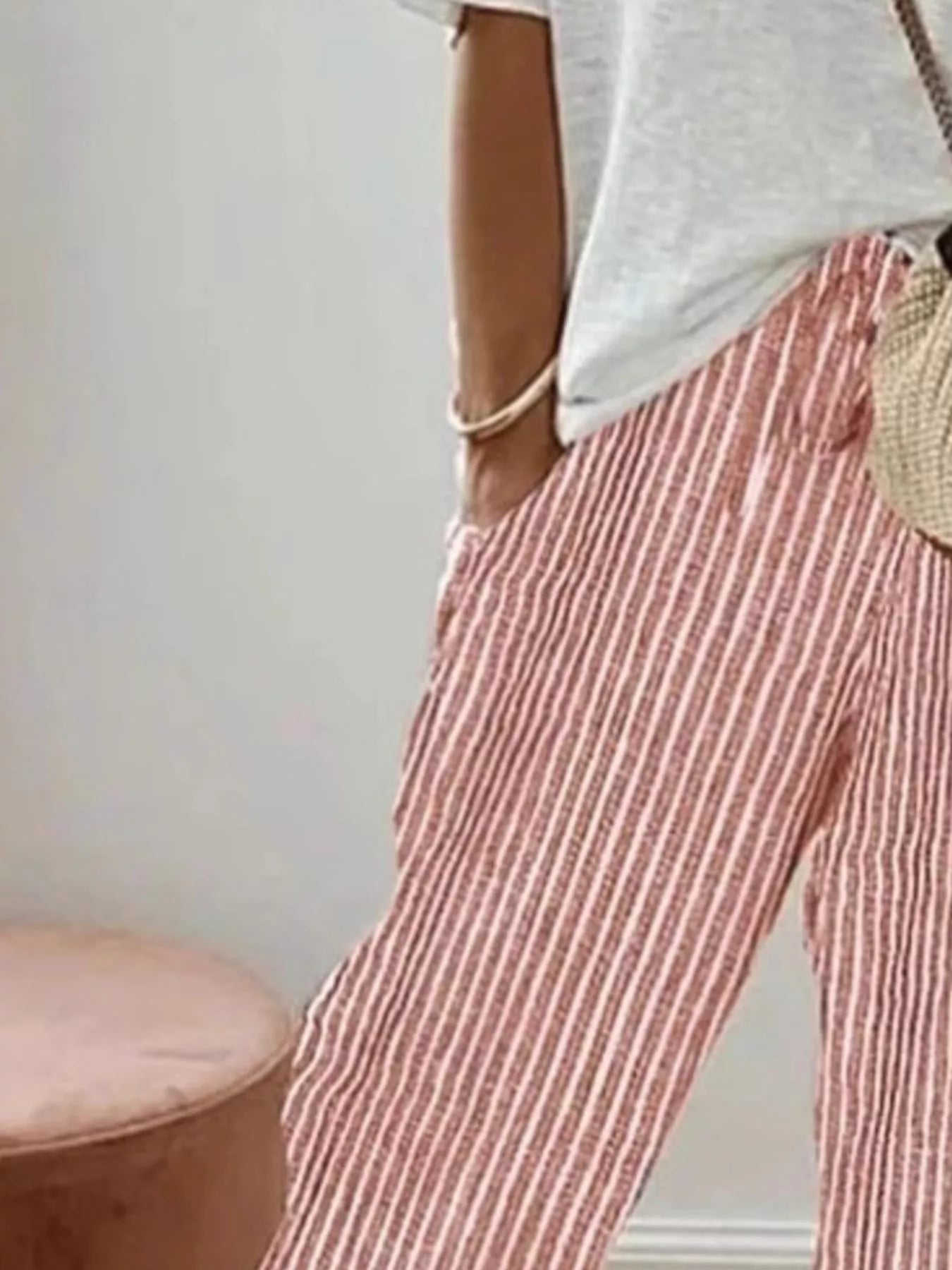 Person wearing red and white striped pants with a neutral background
