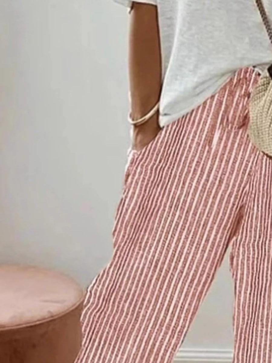 Person wearing red and white striped pants with a neutral background
