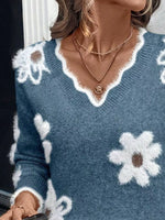 Blue sweater with white flower patterns worn by a person.