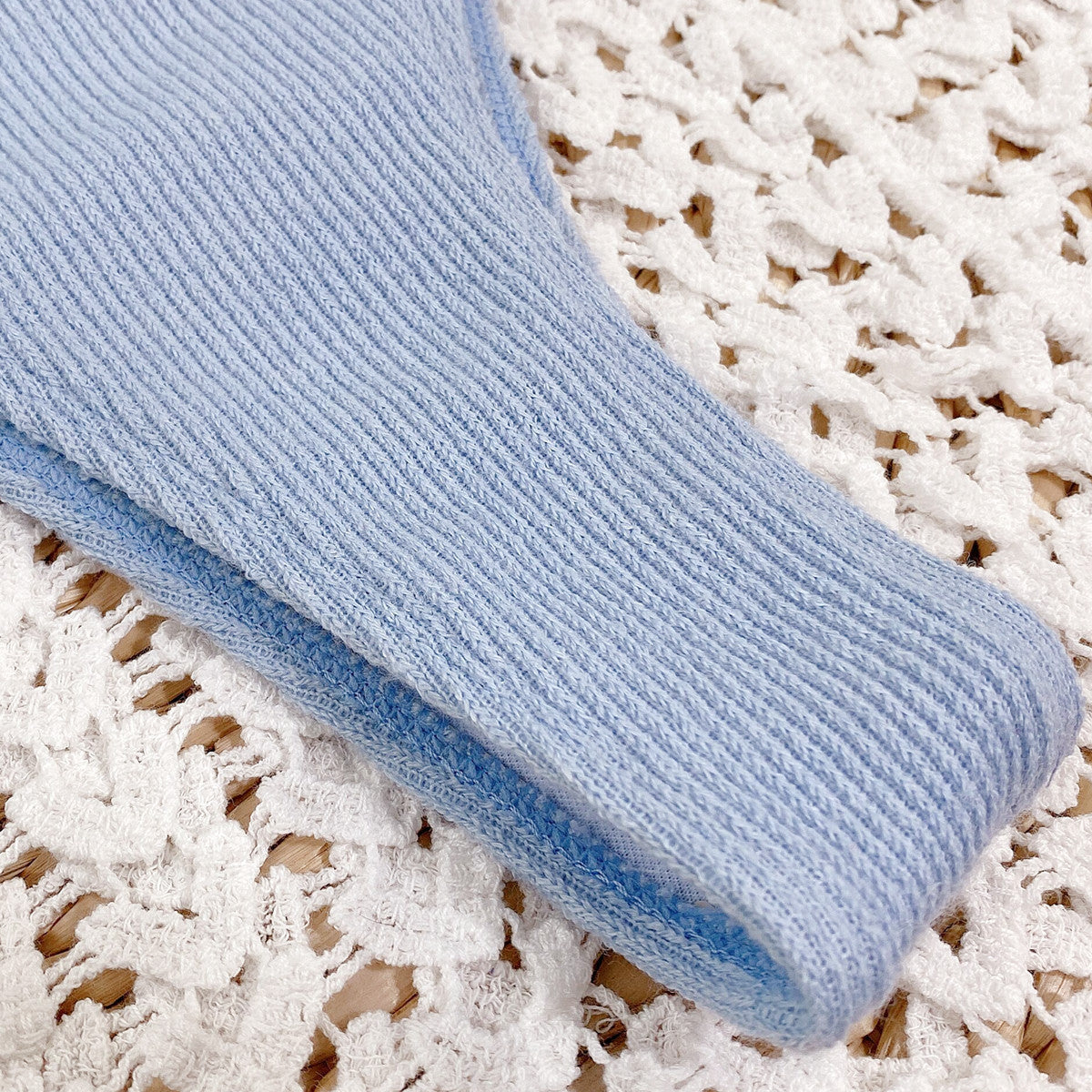 Light blue textured fabric roll on a textured white surface