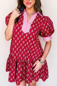 Woman wearing a red floral dress with pink trim against a white background