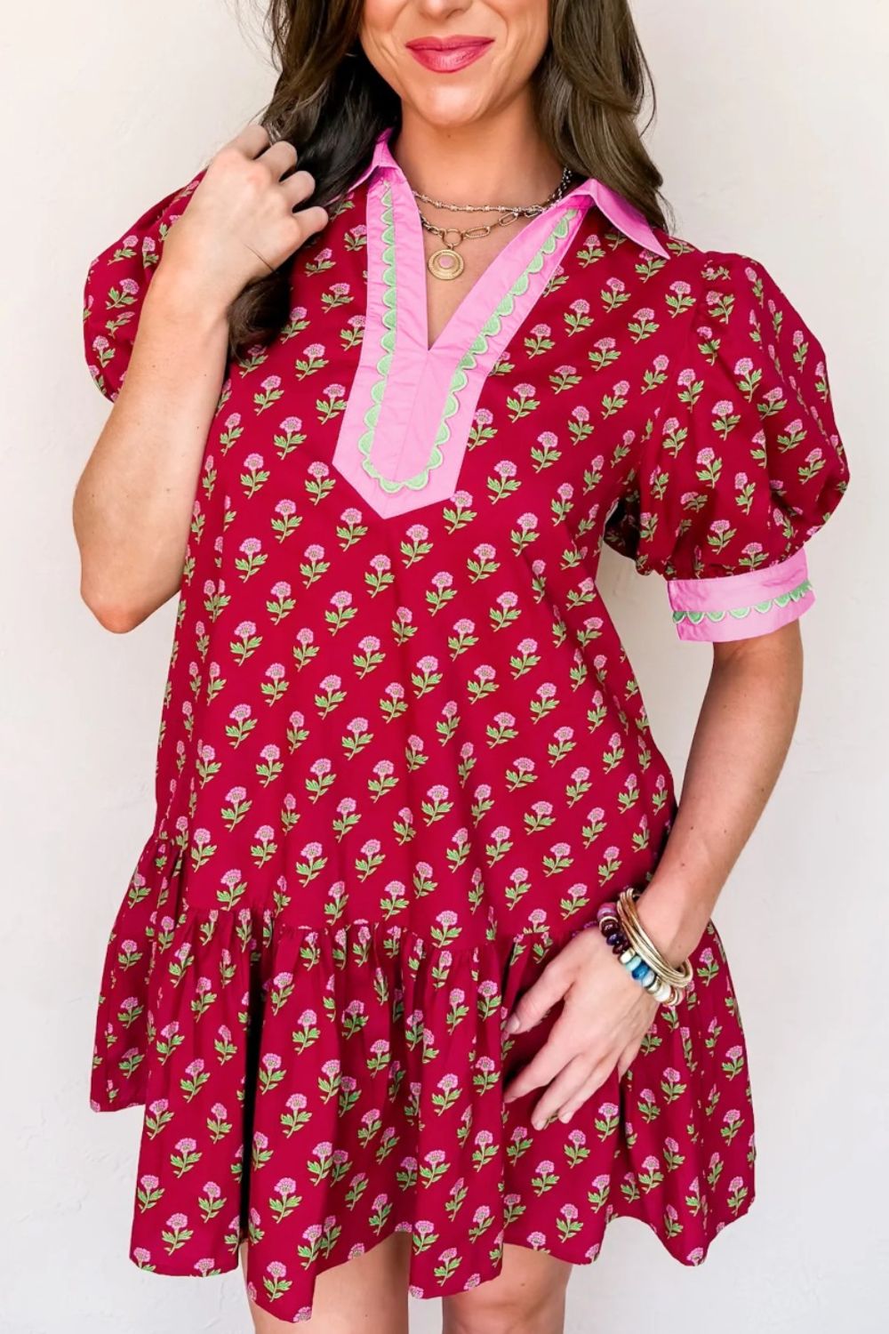 Woman wearing a red floral dress with pink trim against a white background