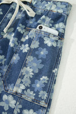 Blue floral-patterned jeans with a white drawstring on a light gray background