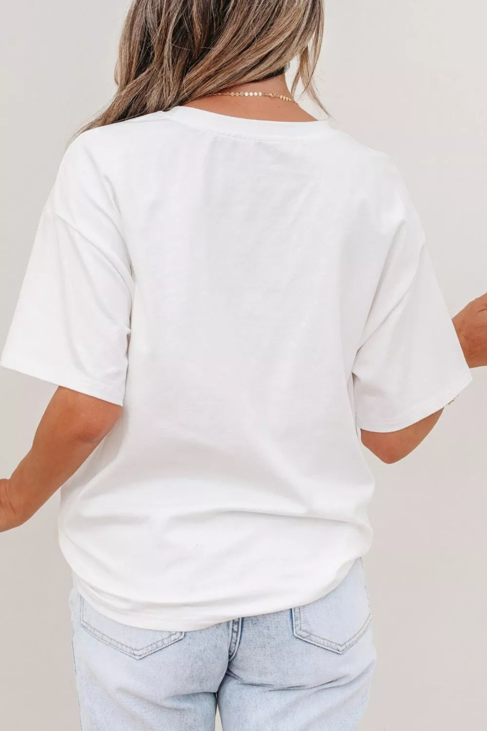 Person wearing a plain white t-shirt and light blue jeans against a neutral background