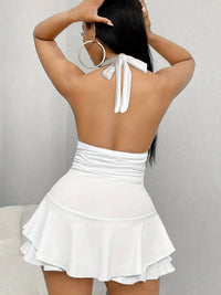 Woman wearing a white dress with a halter neck design on a plain background