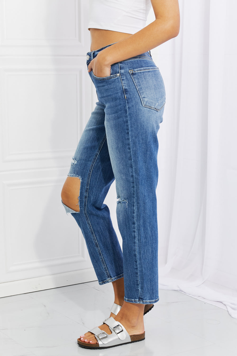 Person wearing blue jeans with cut-out design on a white background