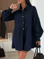Woman wearing a navy blue dress with long sleeves in an indoor setting.