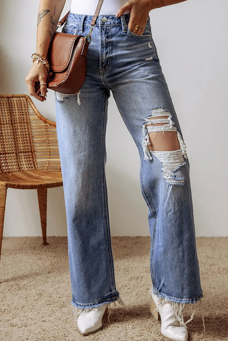 Person wearing ripped blue jeans with a brown leather bag.