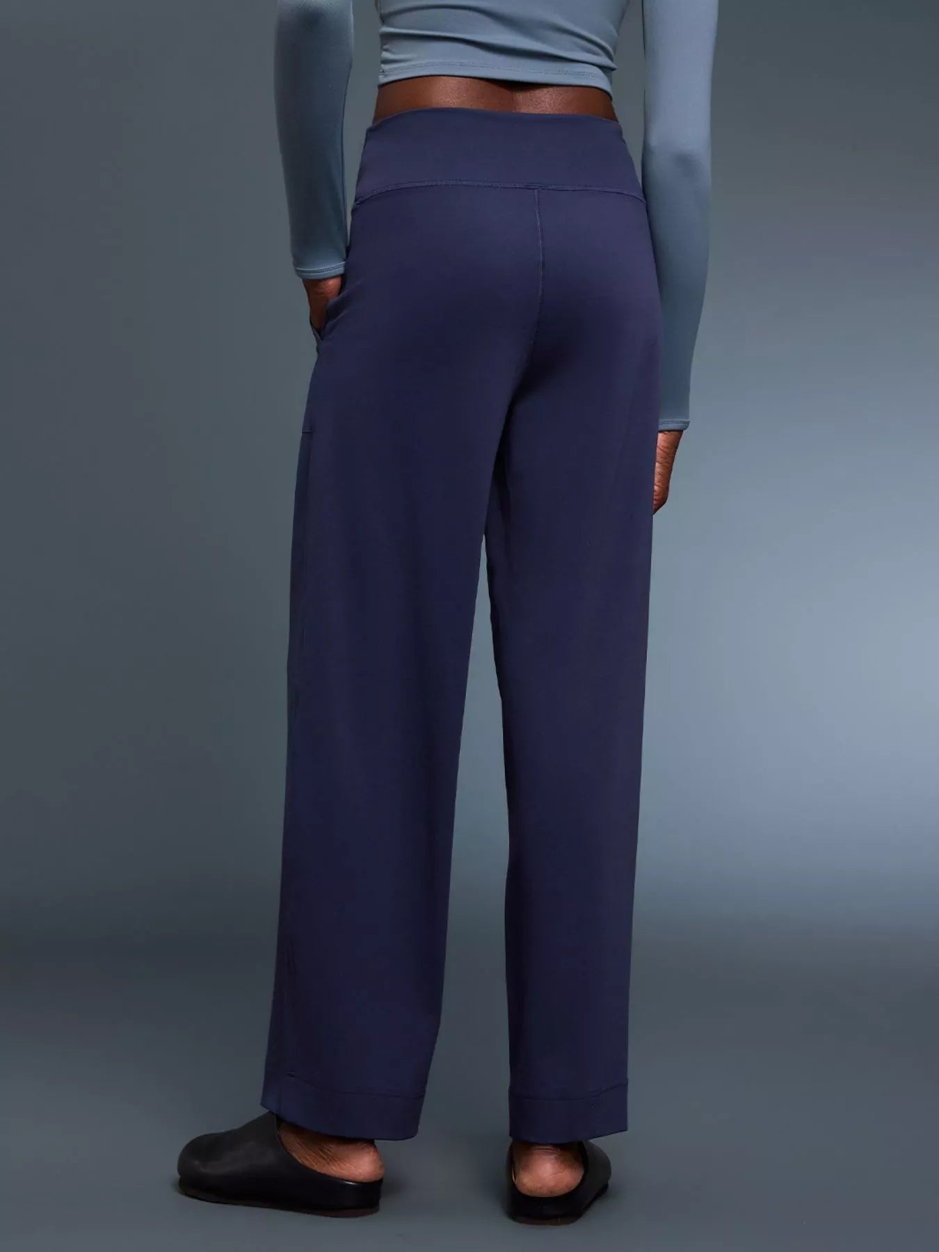 Person wearing navy pants on a gray background