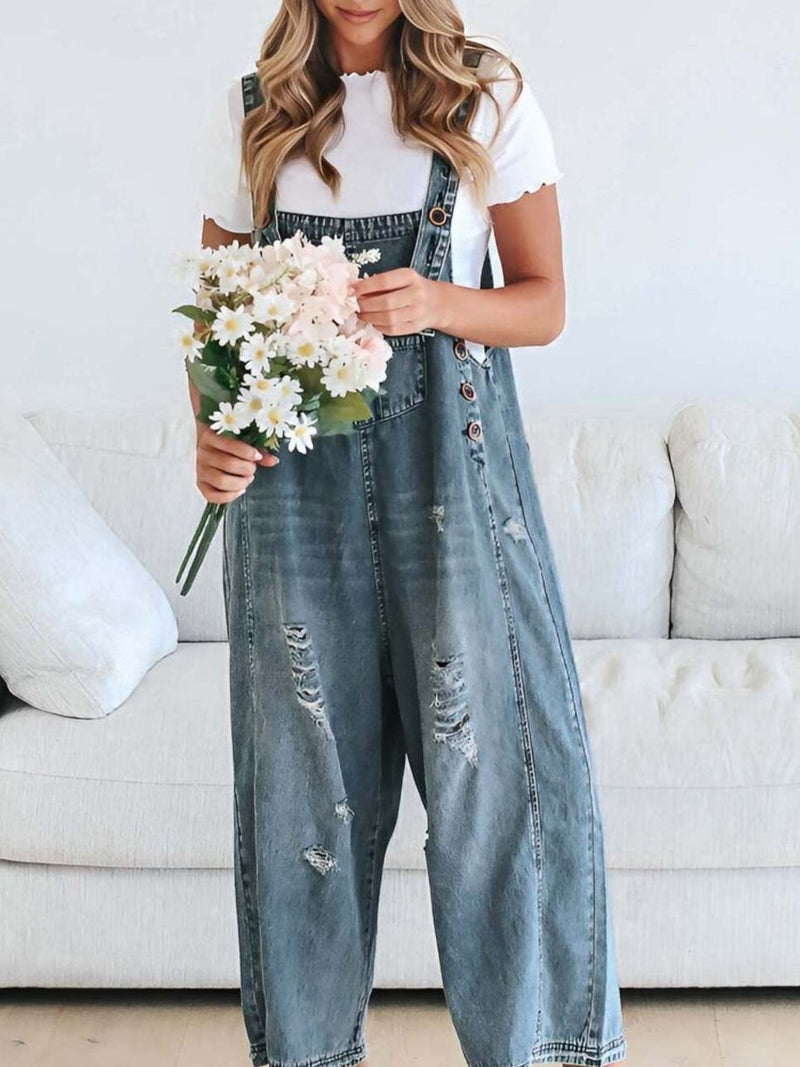 Person wearing denim overalls holding flowers in a living room setting