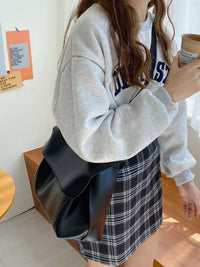 Person holding a black bag and a coffee cup indoors