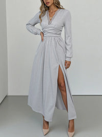 Woman wearing a long gray dress with a slit on a white background