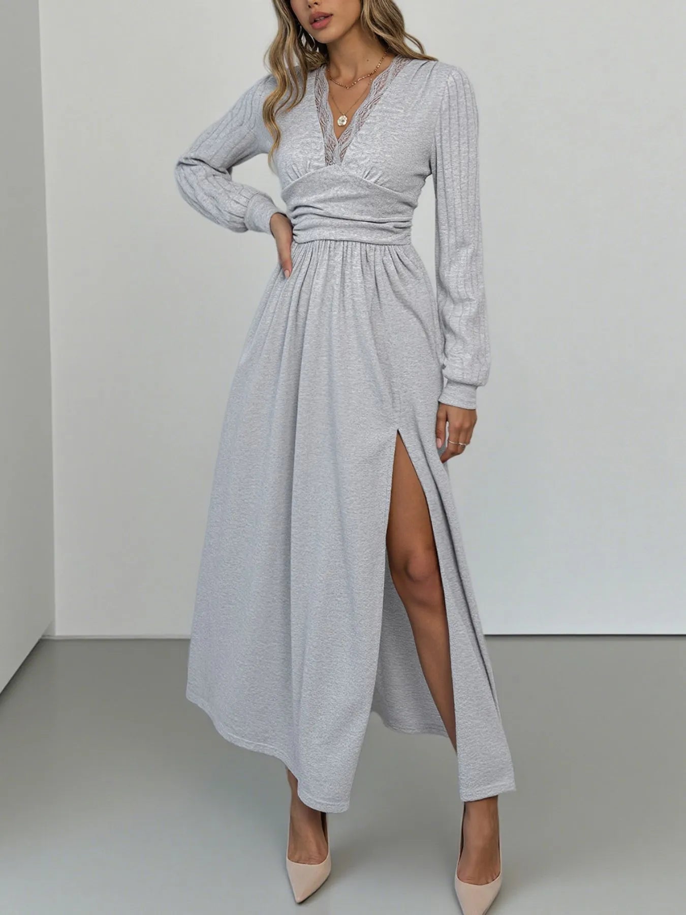 Woman wearing a long gray dress with a slit on a white background