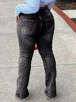 Person wearing black flared jeans on a concrete surface