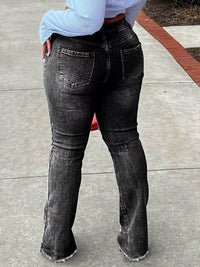 Person wearing black flared jeans on a concrete surface