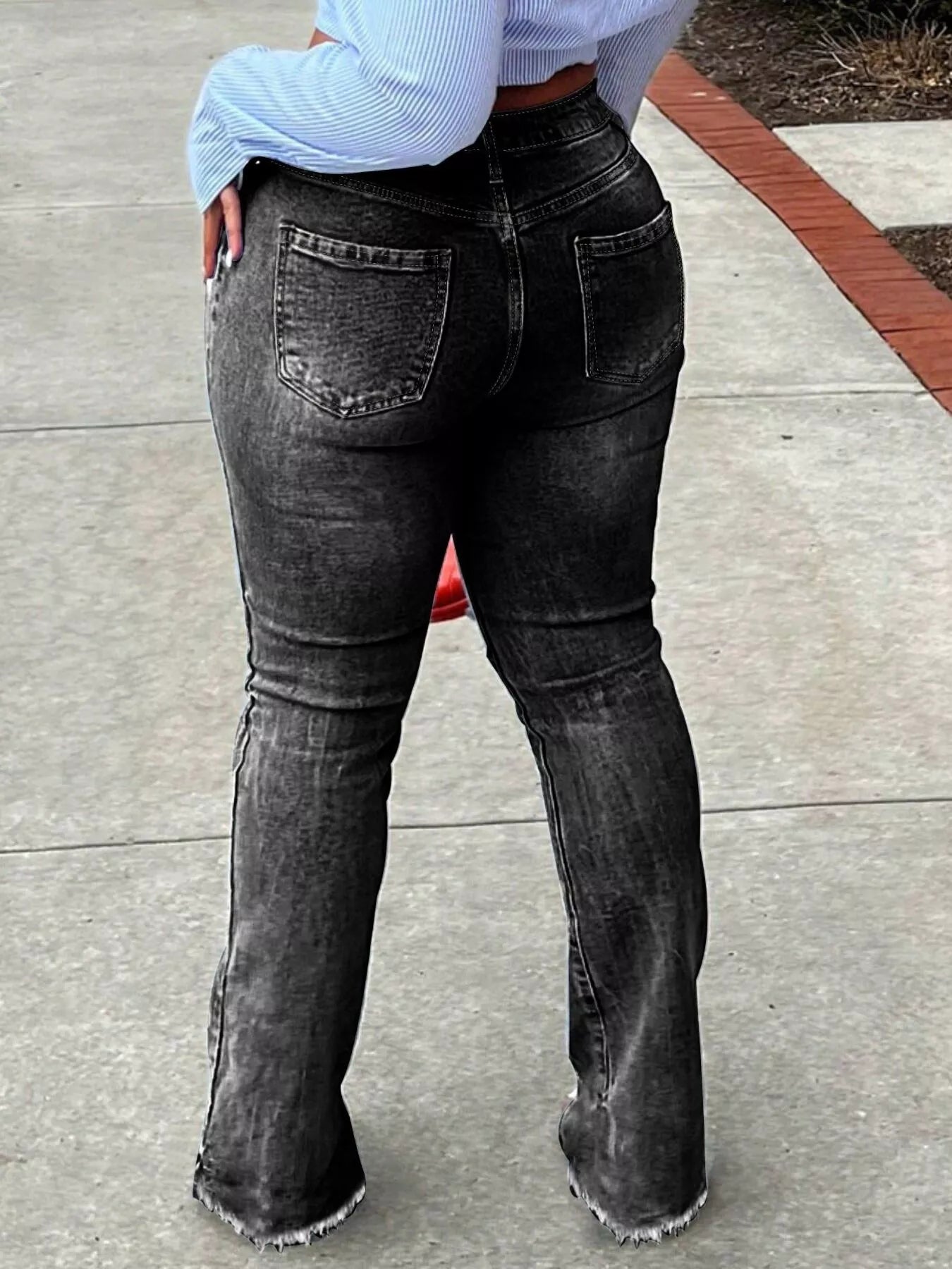 Person wearing black flared jeans on a concrete surface