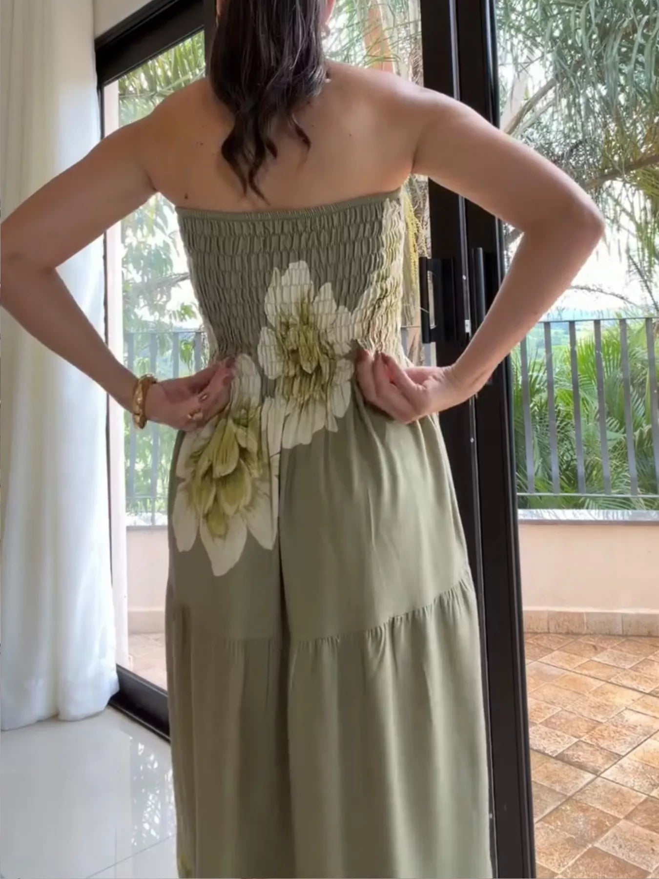 Woman wearing a green strapless dress with floral patterns indoors.