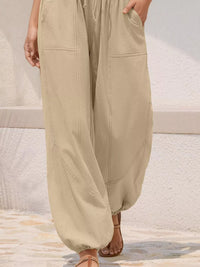 Beige wide-leg pants worn by a person on a neutral background