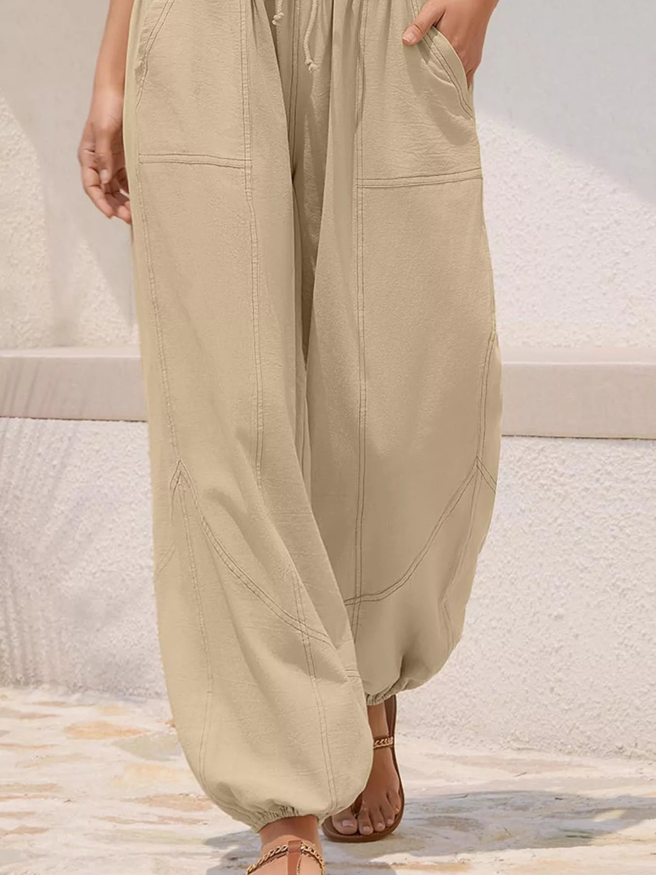 Beige wide-leg pants worn by a person on a neutral background