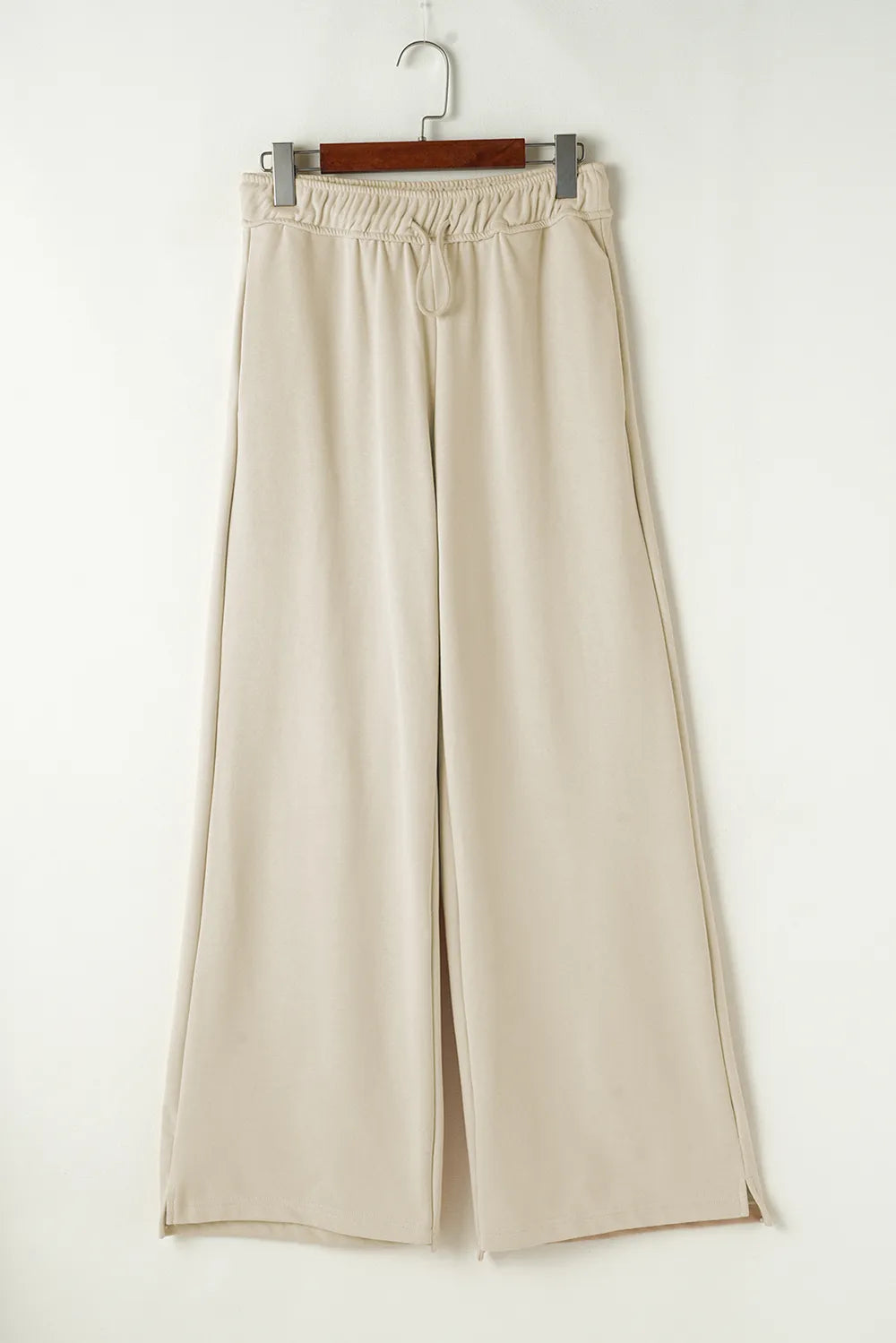 Beige wide-leg pants on a hanger against a white background