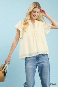 Woman wearing a light yellow blouse and blue jeans against a light blue background