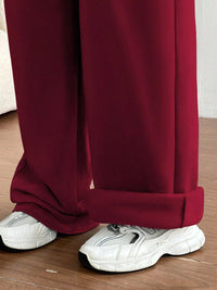 Maroon pants with white sneakers on a wooden floor