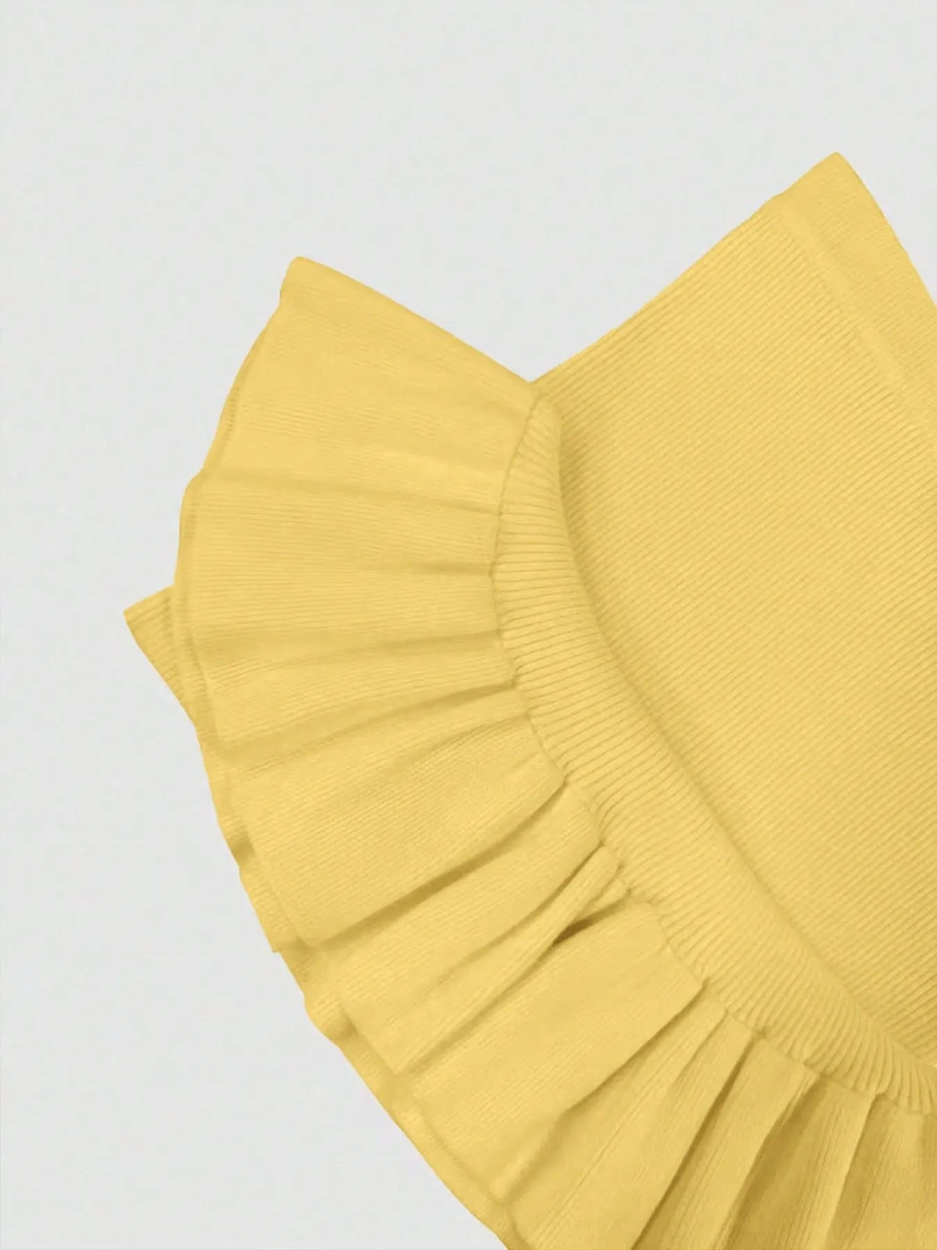 Yellow ruffled fabric on a light gray background