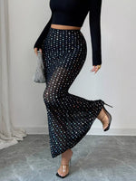 Person wearing a black polka dot skirt with a plain background
