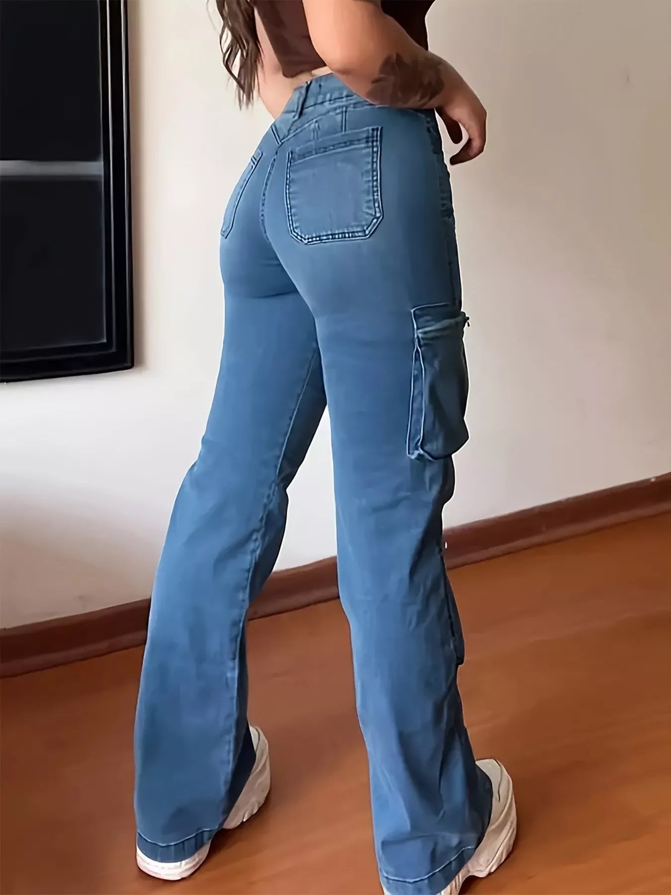 Person wearing blue cargo pants standing indoors on a wooden floor.