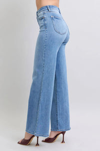 Blue jeans worn by a person on a plain background