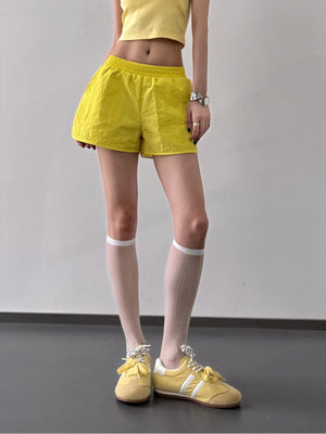 Person wearing yellow shorts, yellow top, and yellow shoes on a plain background