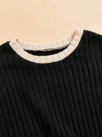 Black ribbed sweater with a white collar on a beige background