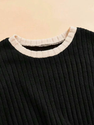 Black ribbed sweater with a white collar on a beige background