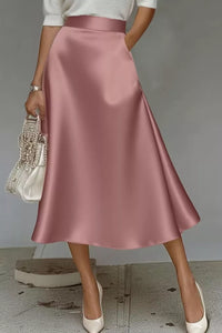 Person wearing a pink satin skirt with a plain background
