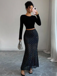 Woman in black long-sleeve top and polka dot skirt taking a mirror selfie.
