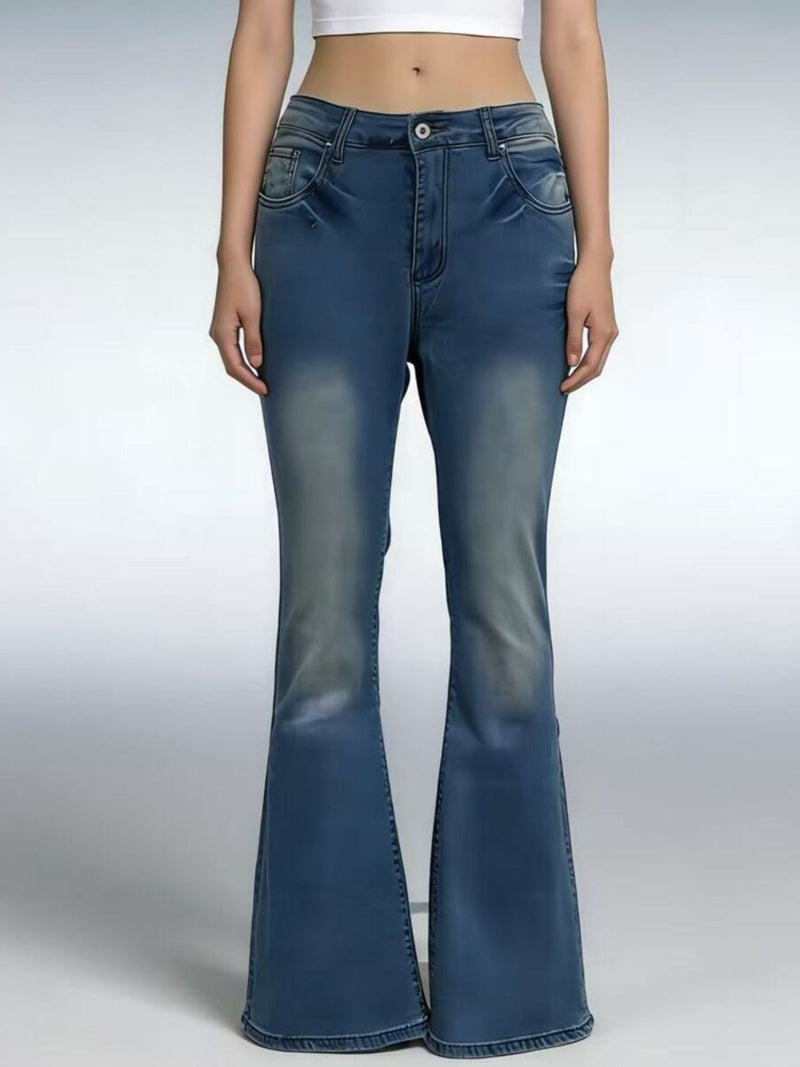 Blue flared jeans worn by a person on a gray background