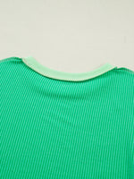 Close-up of a green textured fabric with a light green trim on a beige background