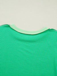 Close-up of a green textured fabric with a light green trim on a beige background