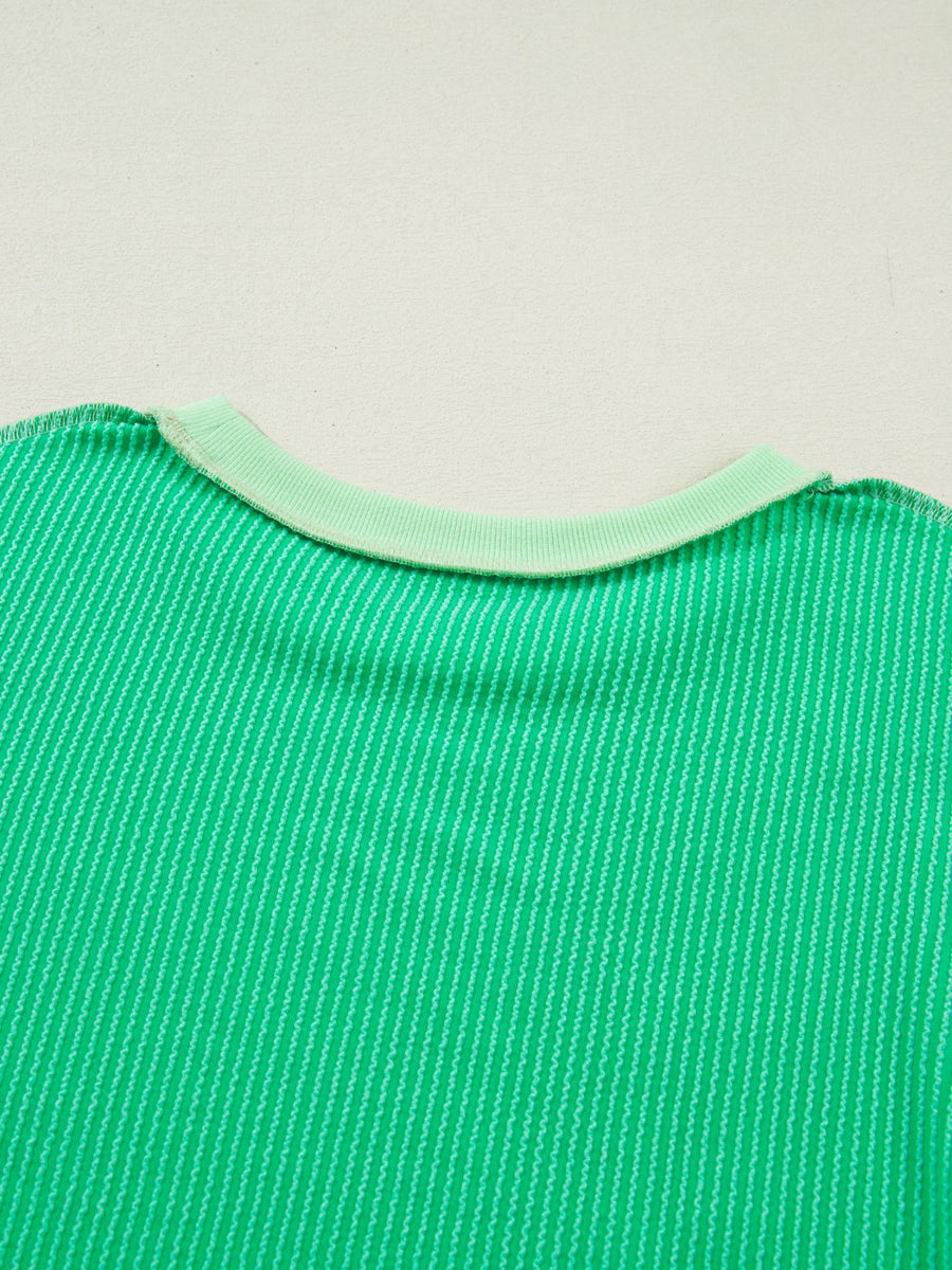 Close-up of a green textured fabric with a light green trim on a beige background